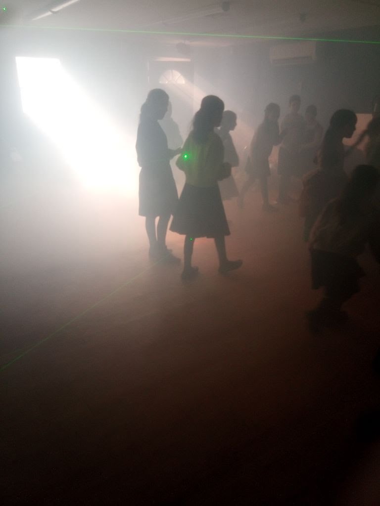 Girls dancing at a glow party with fog and laser lights
