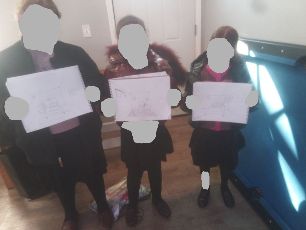 Girls holding up their perspective room sketches