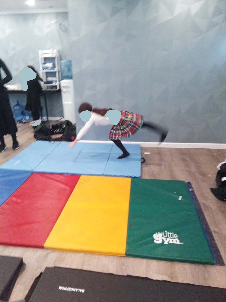 Girl tumbling on a colorful gym mat