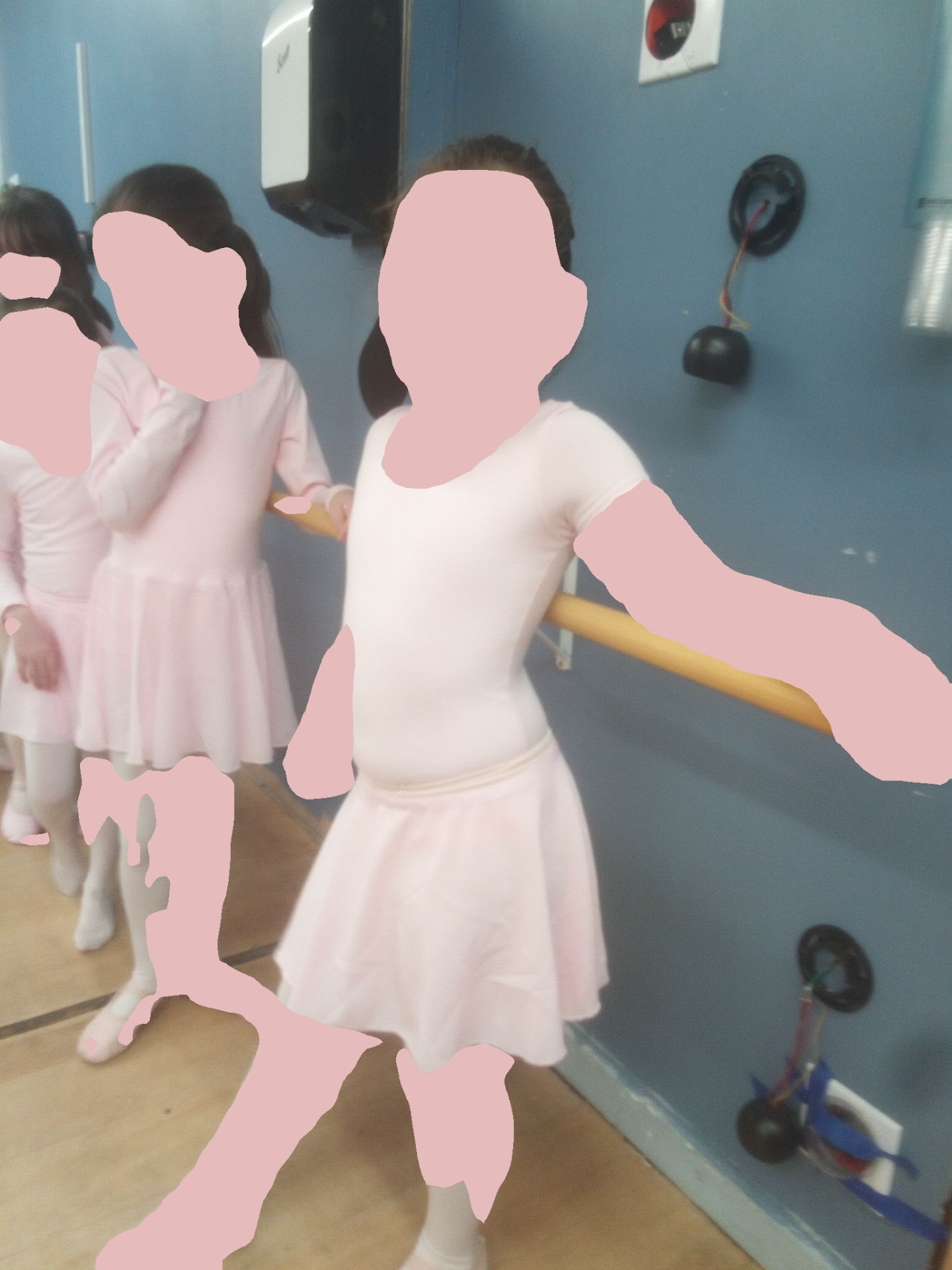 Young ballerinas in pink leotards at the ballet barre